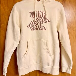LOVE NEVER FAILS CREAM UNISEX HOODIE